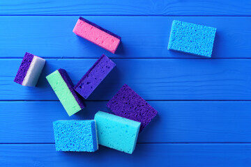 Cleaning sponges on blue wooden background flat lay