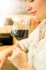 Young attractive woman, tasting wine in a wine store, enjoying glass of tasty wine