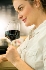 Young attractive woman, tasting wine in a wine store, enjoying glass of tasty wine
