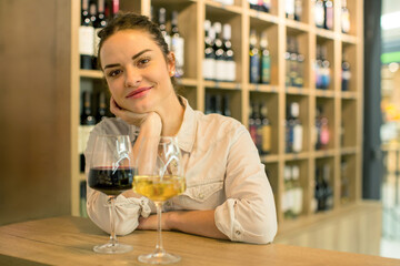 Young attractive woman, tasting wine in a wine store, enjoying glass of tasty wine