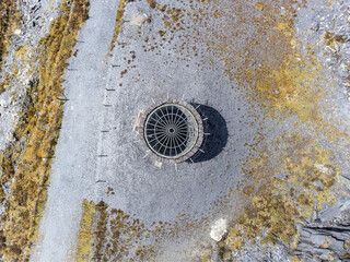 Old abandoned coal pit mine shaft. End of the mining industry capped to make safe at slate quarry. Aerial view from drone of industrial spooky dark mineshaft colliery entrance.