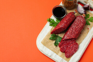Сoncept of tasty food with salami sausage on orange background