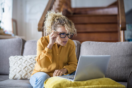Surprised and worried adult woman reading bad notification on laptop computer at home in online work activity. Security and shopping modern concept people