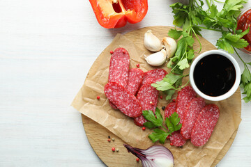 Сoncept of tasty food with salami sausage on white wooden background