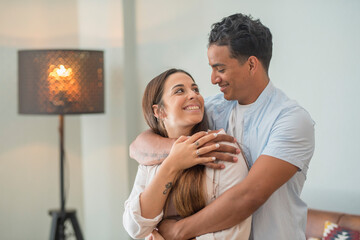 Love and tenderness young adult interracial couple at home. Concept of new house and life together with boy and girl hugging and smiling together with love and romance