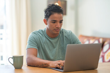 Modern black young man work at home with laptop computer surfing the web. Online job activity people at the table in home work place office. Concept of smart working business
