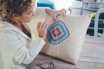 Woman at home doing knit work or crochet on a white pillow to decorate and produce decorations....