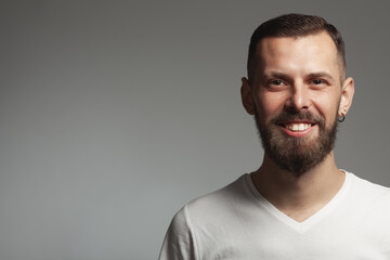 Male beauty concept. Emotive portrait of funny charismatic slim young bearded man posing over light gray background. Perfect haircut. Hipster style. Close up. Copy-spave. Studio shot