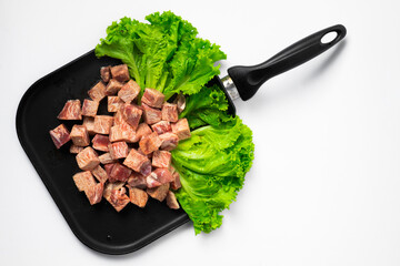 Raw Saikoro Cubes Beef Steak on Grill plate with Lettuce Background. 