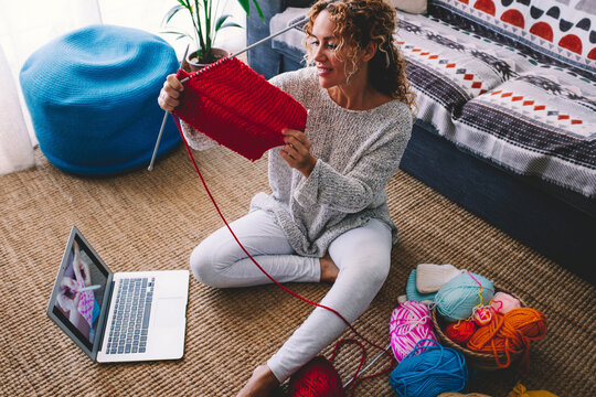 Modern woman do knit work at home thanks to video tutorial online content on laptop computer and wireless connection. Concept of new job opportunity and content creator