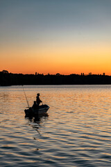 Angler im Boot auf dem See im Sonnenuntergang