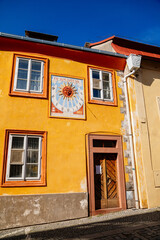 Kolin, Central Bohemia, Czech Republic, 10 July 2021: Narrow picturesque street with colorful renaissance baroque historical houses in medieval town center, sundial with the image of the sun