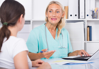 Female doctor working with patient in medical office and writing prescription