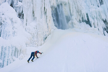 Female ice climber ascending snowy hill