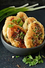 Homemade savory pancakes (Fritters) with minced meat pieces, dill, parsley and green onions, garlic, tomato sauce and chili peppers on a dark background. 
