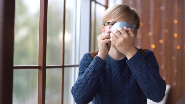 Portrait of a young guy with a mug in his hands. Blond guy with glasses.