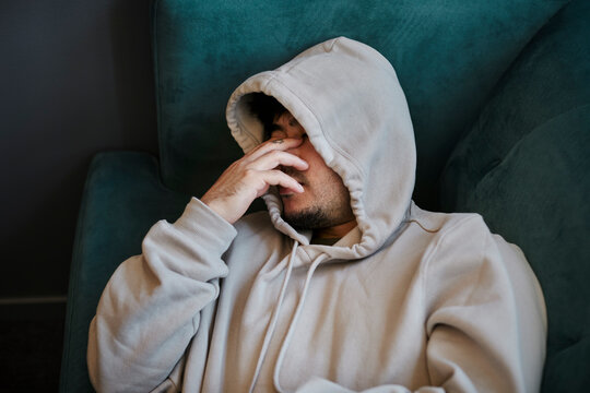 Ill man on sofa with hand covering face