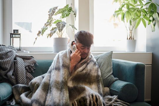 Ill man on sofa checking temperature