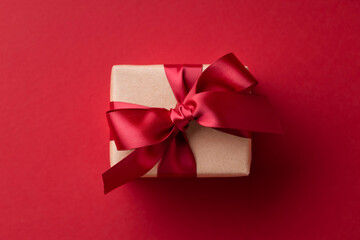 Close up of gift box tied red ribbon on red background.