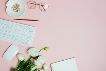 Woman working space with computer, glasses, roses and notebook over the pink background. 