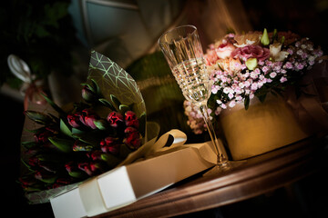 Naklejka na ściany i meble On the table are bouquets of flowers and glasses of champagne on the background of gifts.