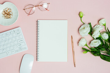 Notebook with computer, glasses and white roses over the pink background. 