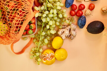 Flat lay Mesh grocery shopping eco friendly bag with fruits on orange canvas background, Zero waste cconcept, Local farmers market, shopping mall, top view, copy space, Plastic free items.