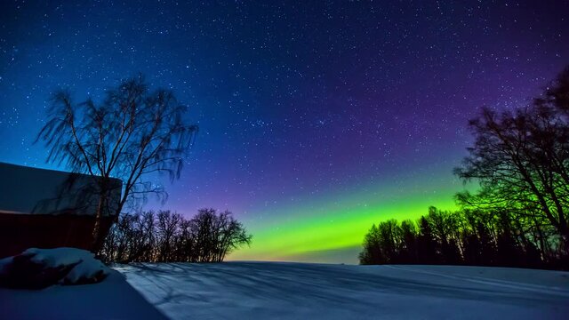 5K Time lapse shot of moving stars at colorful sky and green glowing Polar Lights during cold winter day at night - Bright full moon and flying shooting stars