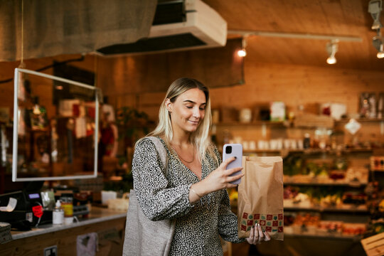 Woman taking photos in shop with organic food