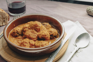 Meatball stew with tomato sauce in earthenware casserole dish.