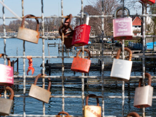 Love locks hang on a grid, in the background is a lake with a marina
