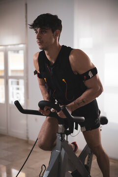 a young athlete riding a bike with an electrostimulation vest in a beauty clinic.