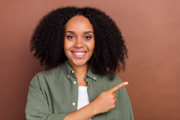 Photo of lovely brunette young afro hairstyle lady index empty space wear military shirt isolated on brown color background