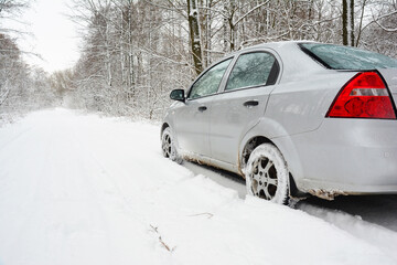 Obraz na płótnie Canvas Driving a sedan car in deep snow. Driving a gray sedan car through a snowy winter forest. Driving home for Christmas.