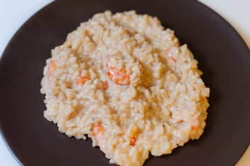 Risotto with shrimp in cream sauce on a dark plate
