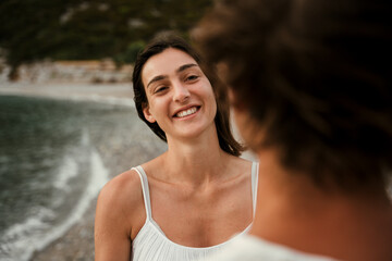 Caucasian female smiling at boyfriend while walking along the beach