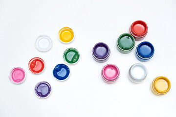 Open jars with gouache of different colors on white background. Gouache paints, top view. Hobby painting. Learning to draw