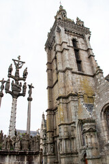 Fototapeta na wymiar Saint-Thégonnec. Clocher et calvaire de l'église de l'enclos paroissial sous ciel blanc. Finistère. Bretagne 