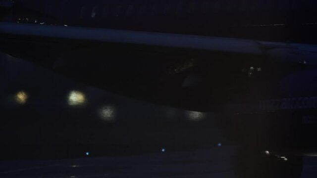 Close-up of airplane headlights. A large plane travels to the runway at night with light breaking through the fog.