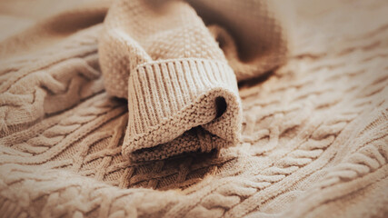 Fototapeta na wymiar The sleeve of a beige soft woolen warm sweater with patterns. Casual warm winter clothes. A jumper for the cold weather. Clothing made of natural materials.