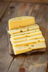 Sliced maasdam cheese on a wooden surface.