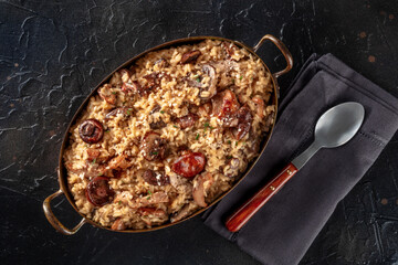 Mushroom risotto, rustic Italian rice dish, shot from above on a black slate background