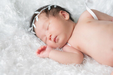 Newborn baby girl wearing angel wing.