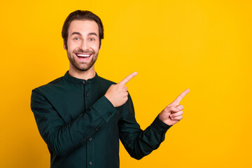 Photo of shocked excited young guy dressed smart casual clothes smiling pointing two fingers empty space isolated yellow color background