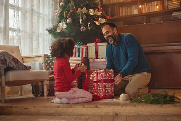 Caucasian father and mixed race daughter wrapping gift for mother - obrazy, fototapety, plakaty