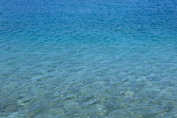Blue transparent sea water texture. Tranquil clean ocean water background. Summer vacation concept.