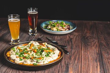 Two glass of beer and autumn or fall food over black background on rustic wooden table.