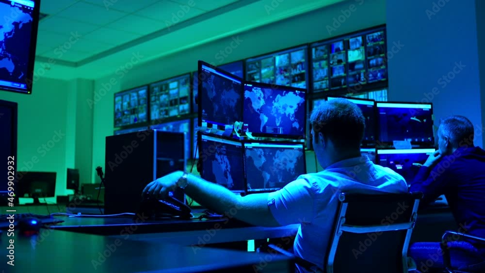 Wall mural male workers sitting near computers on monitoring room and working . programmers or engineers using 