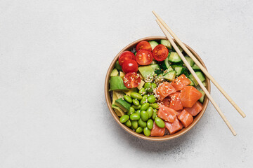 Salmon, avocado, cucumber, tomato, edamame beans and rice poke bowl on light gray background