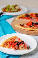 Vegetable salad with roasted meat and cheese and Sliced whole salami pepperoni pizza on a wooden table.